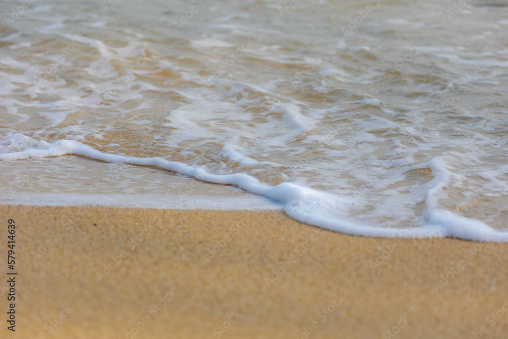 Selective focus of sand beach with sea wave, White bubbles on shoreline while sea wave approaching, Sand texture with free copy space, Beautiful nature pattern background. Selective focus of sand beach with sea wave, White bubbles on shoreline while sea wave approaching, Sand texture with free copy space, Beautiful nature pattern background.