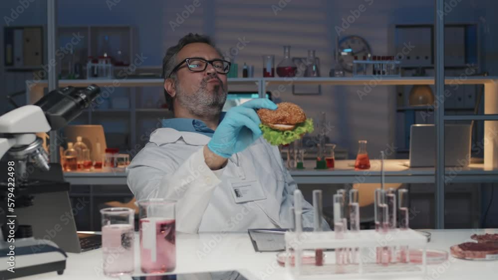 Hungry mature male researcher in gloves and lab coat sitting by