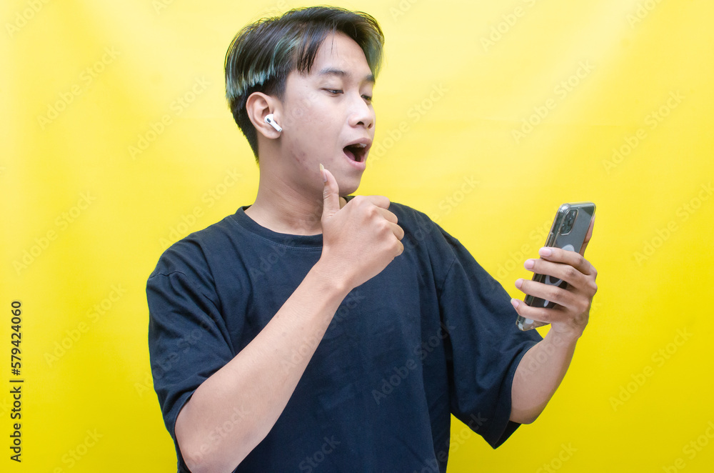 An enthusiastic Asian man with peek-a-boo hair is using airpods while dancing joyfully, checking his phone, and listening to music. An enthusiastic Asian man with peek-a-boo hair is using airpods while dancing joyfully, checking his phone, and listening to music.