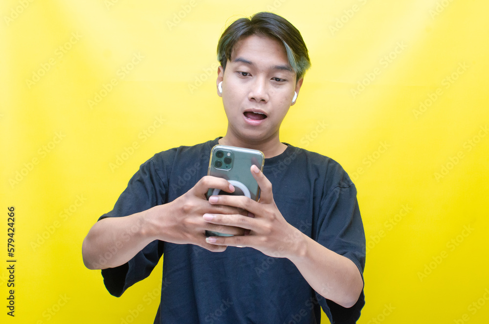 An enthusiastic Asian man with peek-a-boo hair is using airpods while dancing joyfully, checking his phone, and listening to music. An enthusiastic Asian man with peek-a-boo hair is using airpods while dancing joyfully, checking his phone, and listening to music.