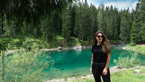 Fototapeta Naklejka Na Ścianę i Meble -  Caucasian girl wearing black outfit and standing by a lake in natural area in Davos, Switzerland