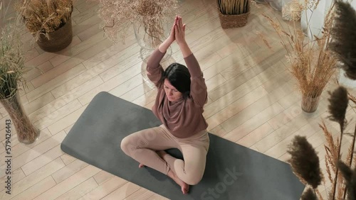 Woman at her 40s doing yoga, stretching her back on the mat on yoga class, top view. Mature woman mental health and self care concept 