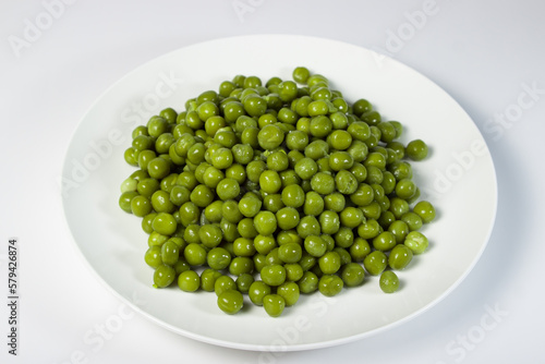 Pickled green peas on a white plate on a white background
