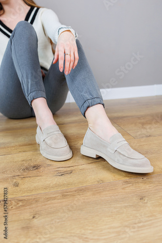 Female legs close-up in gray shoes without heels. Women's comfortable summer casual shoes. Gray women's spring shoes