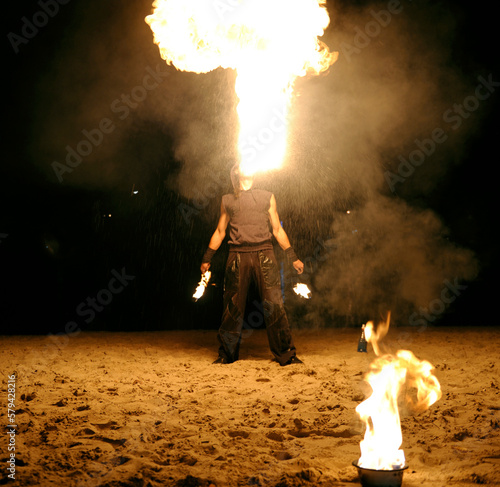 Canvas Print Man fire juggler performing at night on a sandy beach