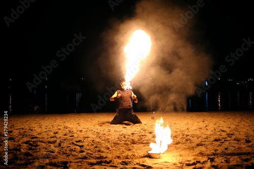 Man fire juggler performing at night on a sandy beach
