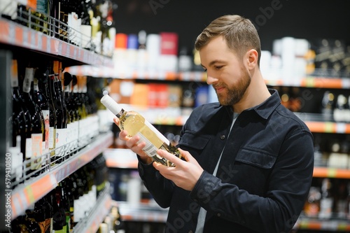 Fototapeta Man in a supermarket choosing a wine