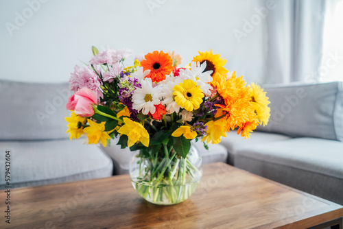 Wallpaper Mural Vase with huge multicolor various flower bouquet on the coffee table with blurred background of modern cozy light living room with gray couch sofa. Giving flowers. Mother's day, birthday gift. Torontodigital.ca