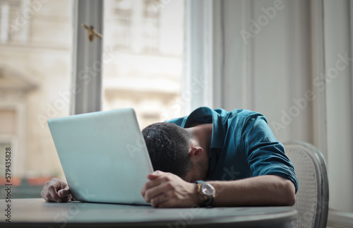 depressed man with head leaning on computer