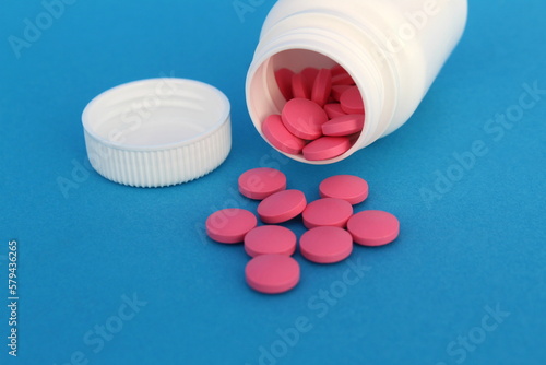 On a blue background lies a container with medicine pills. 