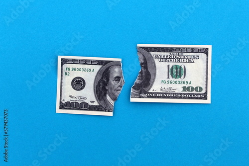 A torn dollar bill lies on a blue background. photo