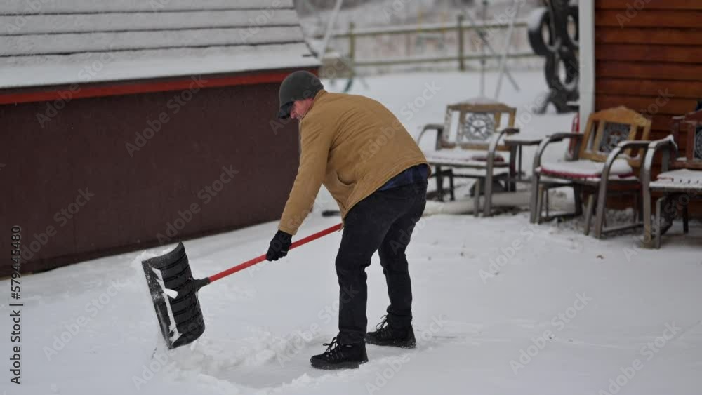 Caucasian man shoveling snow in the backyard during winter Caucasian man shoveling snow in the backyard during winter