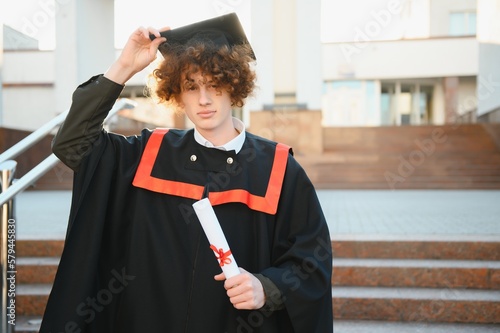 Handsome graduate in graduation glow with diploma.