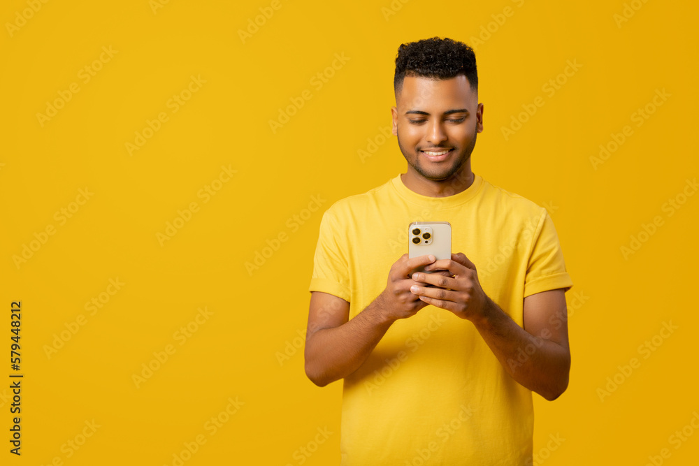 Young Indian 20s man is using his smartphone, sending text messages or browsing the web, enjoying his time using various mobile applications to chat with friends and stay connected online, isolated Young Indian 20s man is using his smartphone, sending text messages or browsing the web, enjoying his time using various mobile applications to chat with friends and stay connected online, isolated