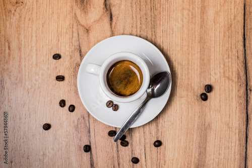 Espresso cup on a wooden table and scattered coffee beans photo