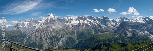 Panoramic shot of the snow-covered mountain tips against a blue sky on a sunny day