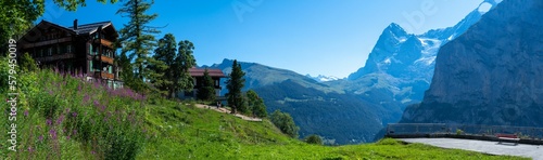 Panoramic shot of the house on top of the hill with mountains and trees in the background