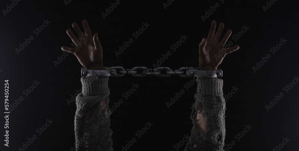 hands with prison chains, black brick wall