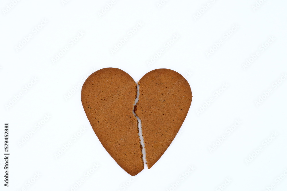 One broken gingerbread heart. Concept of ending love. Small or thin crack. Isolated on a white background. One broken gingerbread heart. Concept of ending love. Small or thin crack. Isolated on a white background.