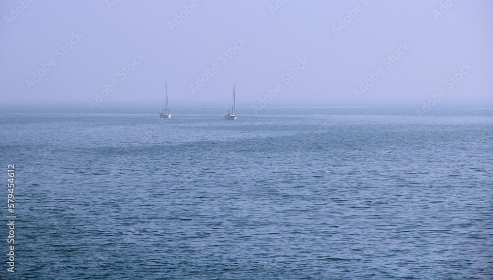 Sailboats in the foggy horizon of the sea
