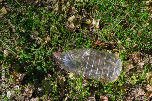 The plastic bottle lies on the grass. The concept of reducing the use of plastic
