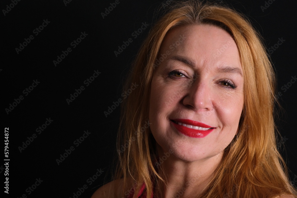 Portrait of a woman. Red lipstick. Brown eyes, blond hair. The background is black. Portrait of a woman. Red lipstick. Brown eyes, blond hair. The background is black.