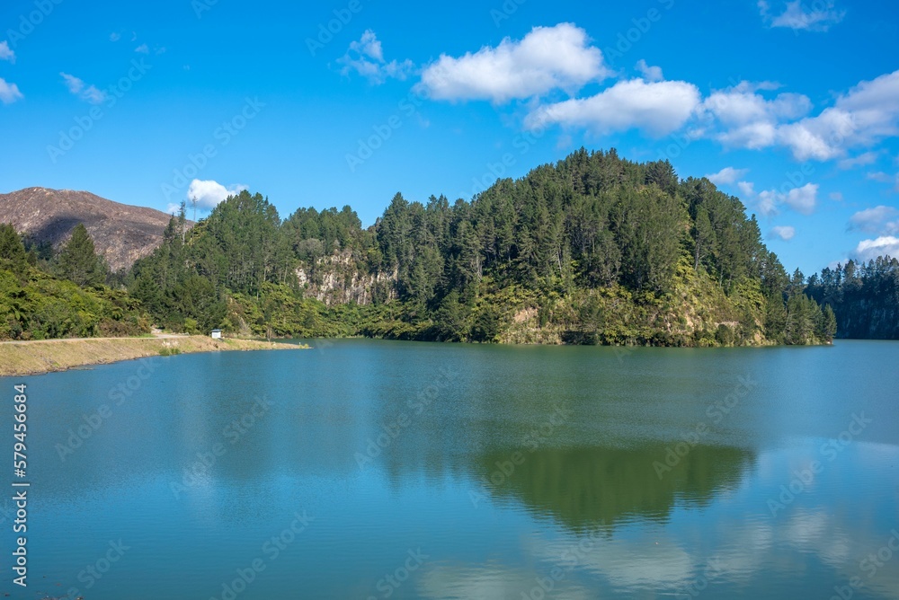 Green trees reflected in calm Matahina Lake in the Bay Of Plenty, New Zealand