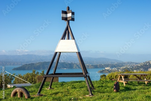 Trigonometrical station on lush green hill overlooking the Wellington harbor on blue sky background photo