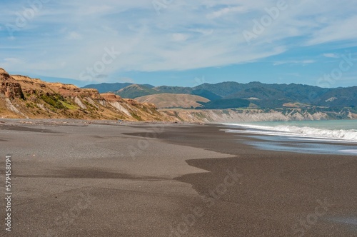 Scenic shot of the empty coast of Palliser Bay in Wairarapa with the beautiful landscape in the back