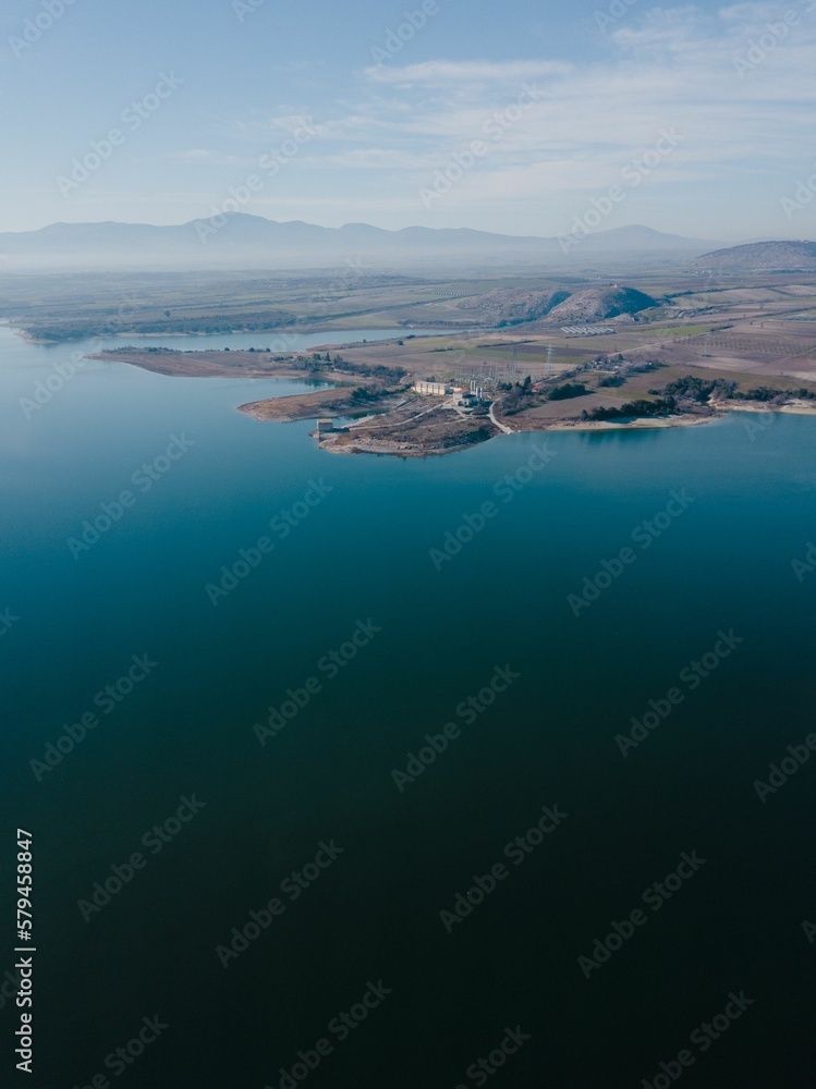 Vertical aerial shot of the coast of a beach with beautiful mountains visible in the back