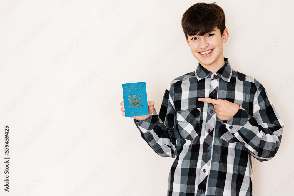 Young teenager boy holding Fiji passport looking positive and happy standing and smiling with a confident smile against white background. Young teenager boy holding Fiji passport looking positive and happy standing and smiling with a confident smile against white background.
