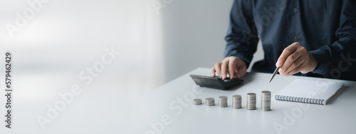 Obraz na płótnie A businessman is keeping a record of his income and expenses, he plans his finances by using his monthly savings to buy funds to make it grow faster