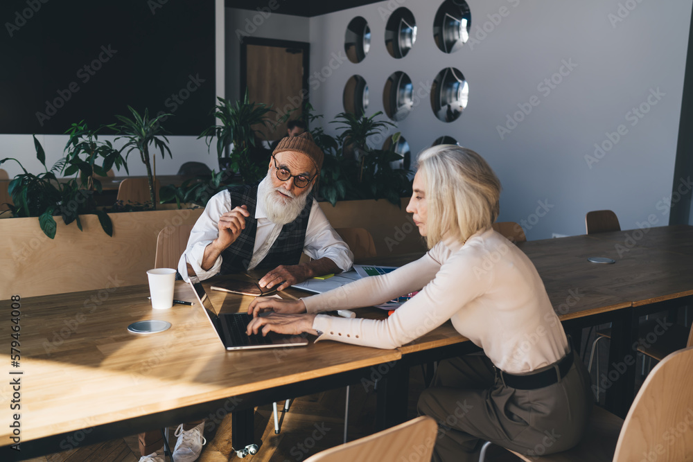Elderly woman typing on laptop keyboard during meeting Elderly woman typing on laptop keyboard during meeting