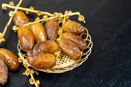 Close-up of Algerian royal dates on a wooden plate on a black background. Ramadan concept.