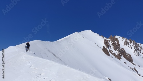 Rear view of a man with hiking poles on snowy mountain peak. Erciyes Mountain, Turkey