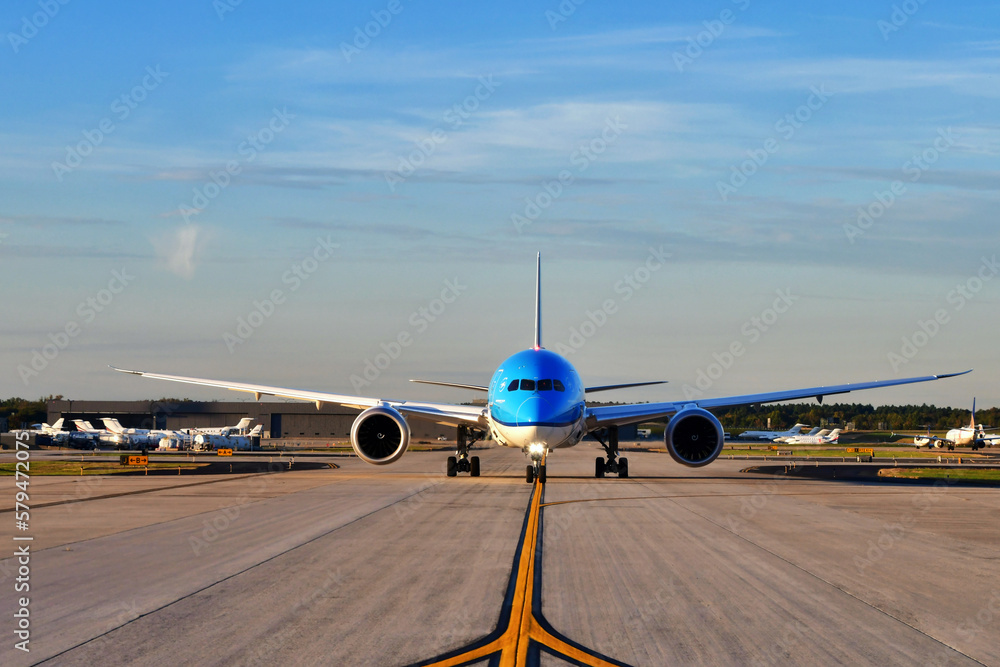 Fototapeta premium A jumbo jet airplane taxing on the runway preparing to take off with the airport in the background