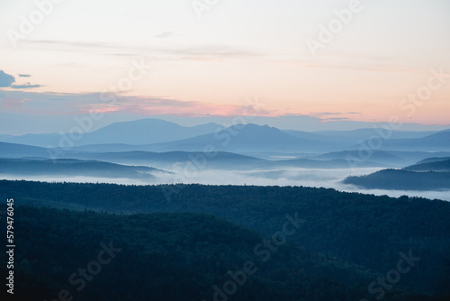 Morning fog filled the lowlands in the river valley  the mountains are visible in the distance  the taiga at dawn of the day  the bluish perspective.