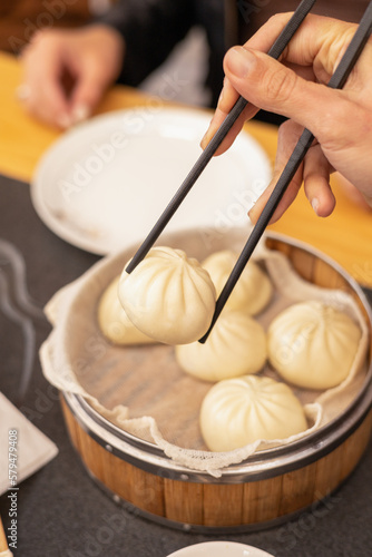 hand with chopsticks taking delicious dumpling from traditional bowl, healthy food ready to eat in restaurant, asian tradition