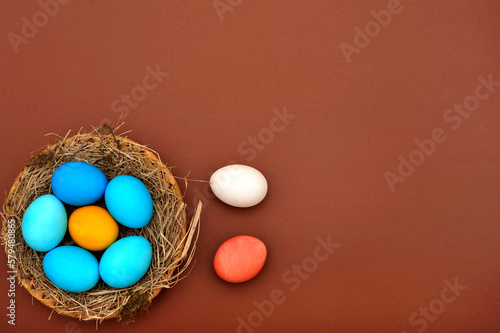   Happy Easter. Easter eggs, painted in different colors in a nest on a terracotta background. Space for text.