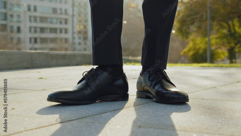 Businessman walk into the frame black new shoes. Legs of a businessman in fashionable shoes. Business concept. Stylish men wears. Low angle. Businessman walk into the frame black new shoes. Legs of a businessman in fashionable shoes. Business concept. Stylish men wears. Low angle.