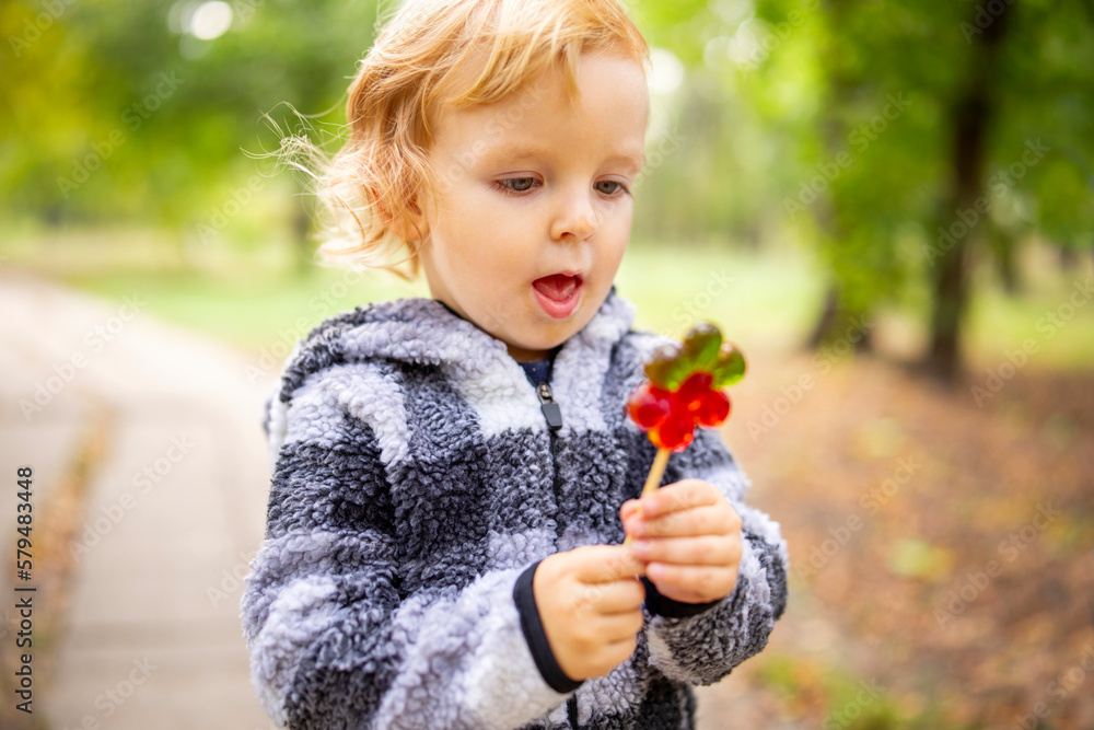 Funny child with candy lollipop, little boy eating big sugar lollipop outdoors Funny child with candy lollipop, little boy eating big sugar lollipop outdoors