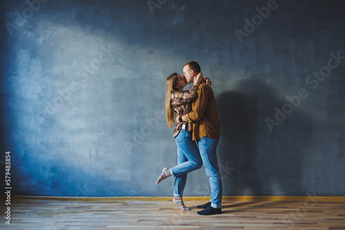 Fototapeta Naklejka Na Ścianę i Meble -  Happy couple in love dressed in shirts, standing on the background of gray wall, looking at empty space, isolated background of gray concrete wall. The concept of a happy couple in love.