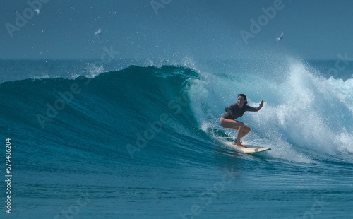 Young woman surfer rides the wave in the Maldives