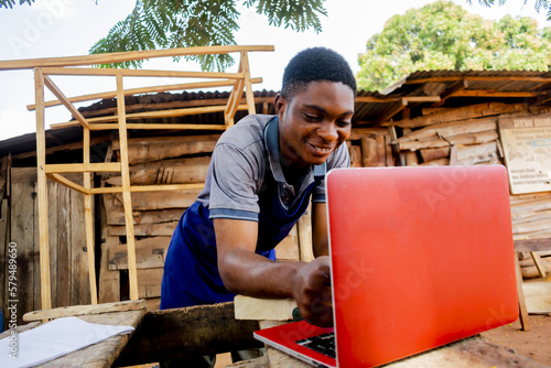 young african carpenter standing holding working calling laptop