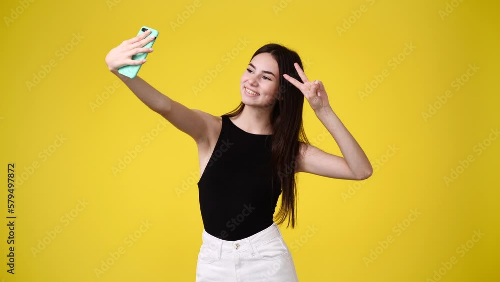 4k video of cute girl using phone and waving hello over yellow background. 4k video of cute girl using phone and waving hello over yellow background.