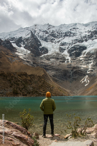 Young man standing on his back in front of the Humantay lagoon in Peru, wearing colourful clothes.