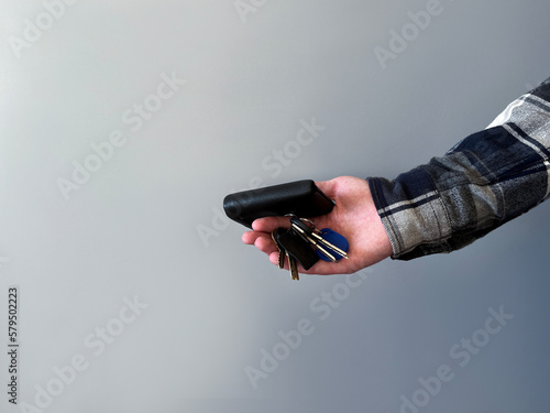 Man in an jeans and a shirt holds wallet and keys on a gray background