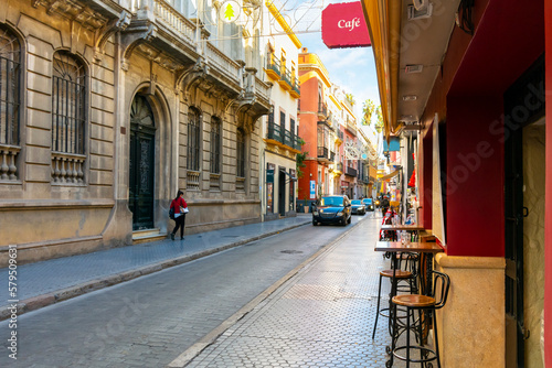 Fototapeta Naklejka Na Ścianę i Meble -  A small sidewalk cafe with tables for two along a street in the downtown district of the Andalusian city of Seville, Spain.