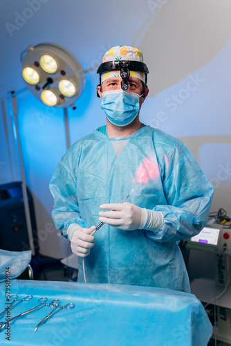 Portrait of professional male surgeon proctologist before operation holding an anoscope in the operating room in hospital. Urgent surgical concept