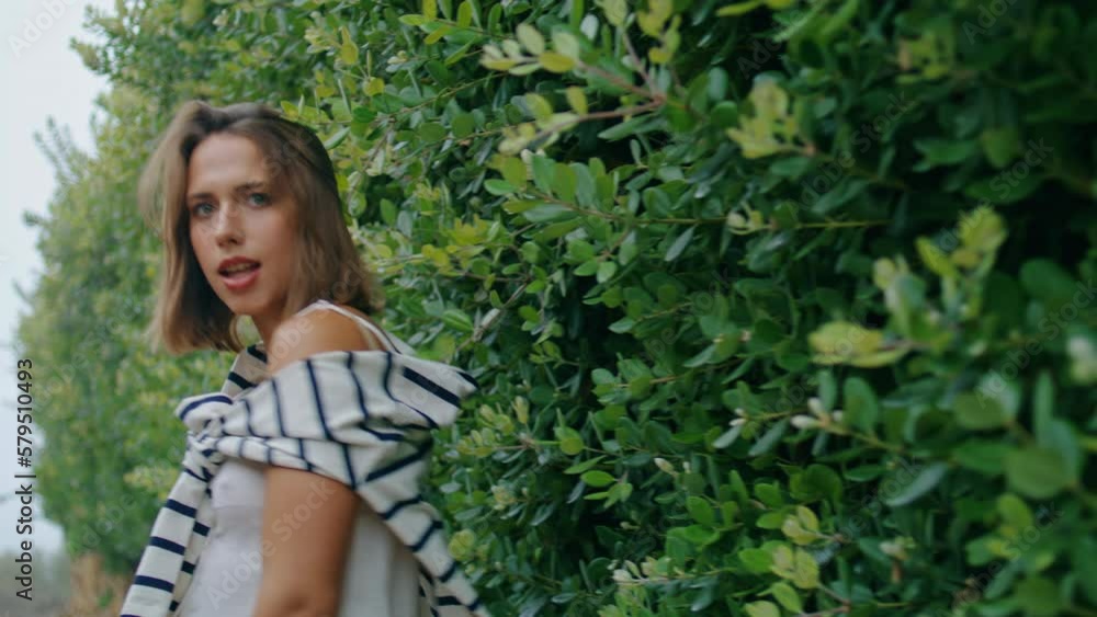 Girl going green leaves street on summer trip. Romantic tourist pose touch bush Girl going green leaves street on summer trip. Romantic tourist pose touch bush